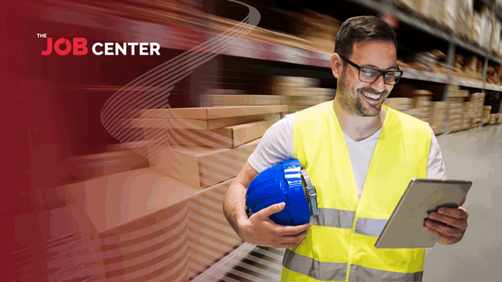 Warehouse worker looks at a clipboard holding a hard hat.