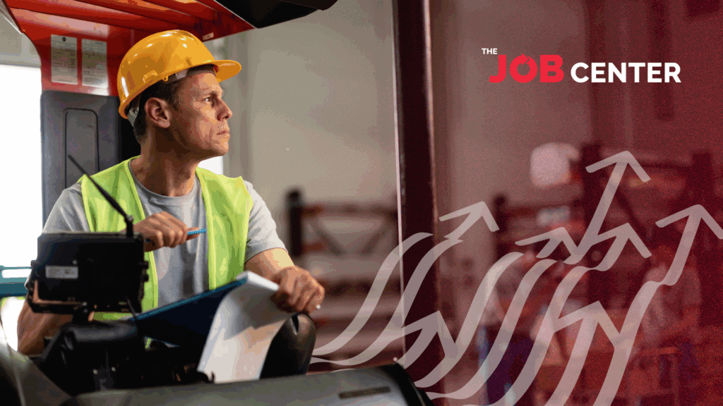 Warehouse worker in safety vest and hard hat operates forklift